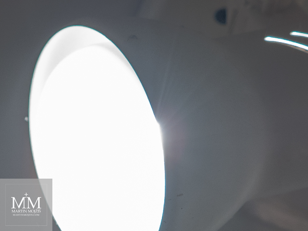Svítící žárovka v bodovém reflektoru v pohledu zblízka. Fotografie vytvořená objektivem Olympus M. Zuiko digital ED 40 - 150 mm 1:2.8 PRO.